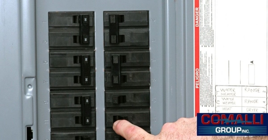 A man flipping a circuit breaker on a home electrical panel.